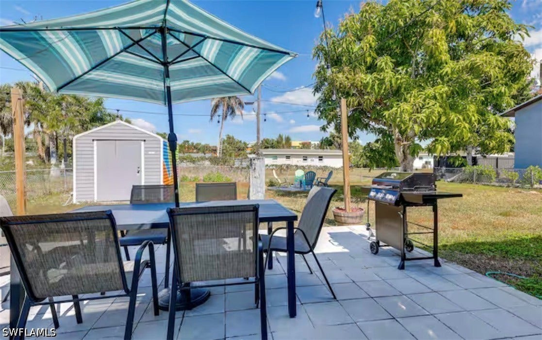 4630 New Haven Drive, Fort Myers, FL 33908 Expansive backyard featuring a gray storage shed, mature tree, and a tiled patio area