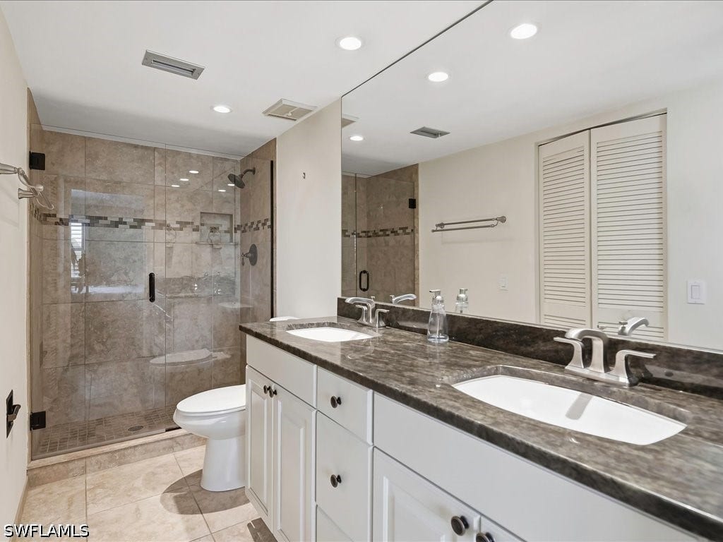 Updated main bath with walls removed, walk in glass and tiled shower, vanity with granite counter, double sink, comfort level toilet. There is a walk-in closet to the left.