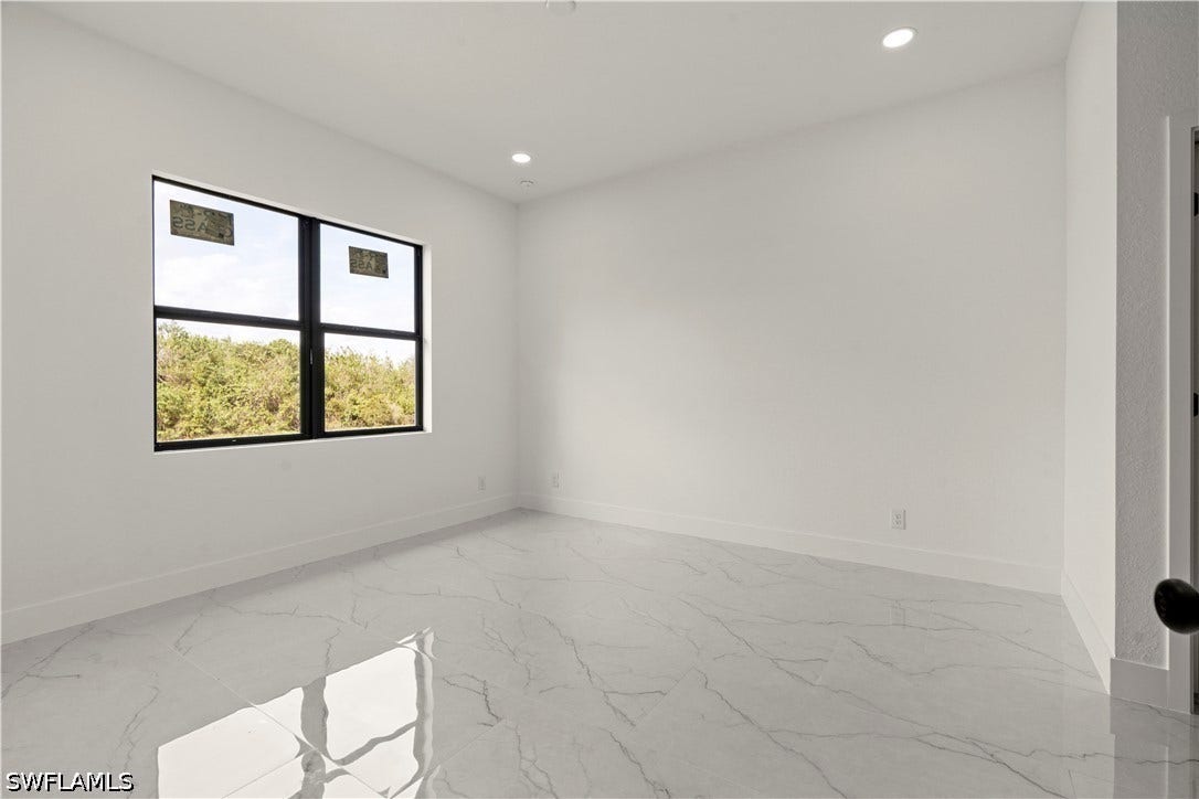 532 Lone Star Lane, Lehigh Acres, FL 33974 Expansive room featuring white walls, recessed ceiling lighting, and a large window with black framing