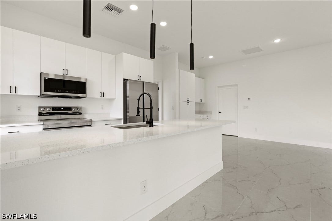 532 Lone Star Lane, Lehigh Acres, FL 33974 White shaker cabinetry with dark hardware and stainless steel appliances