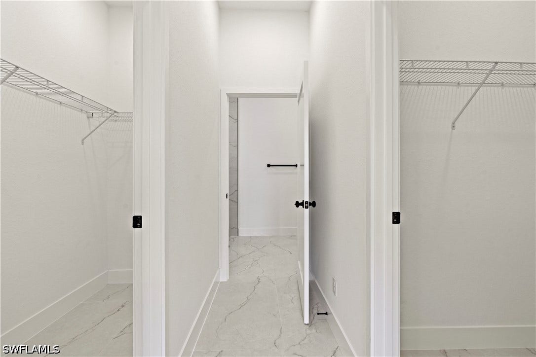 532 Lone Star Lane, Lehigh Acres, FL 33974 Dual walk-in closets with wire shelving, white doors with matte black hardware, and marble-look tile flooring