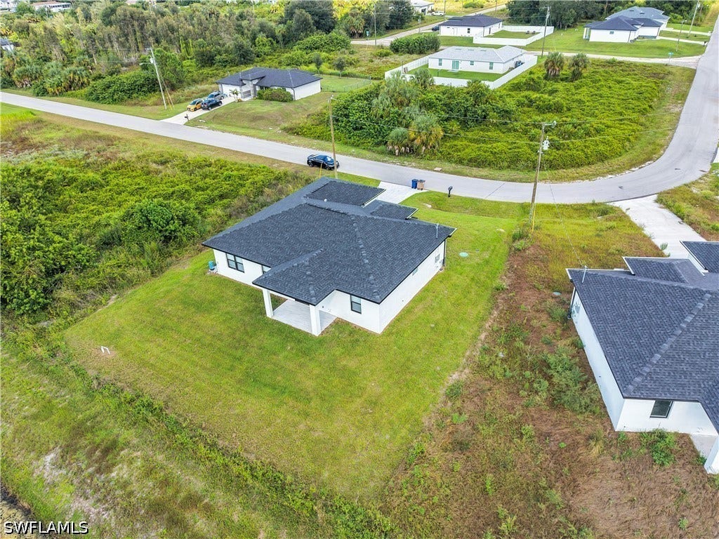 532 Lone Star Lane, Lehigh Acres, FL 33974 White exterior with a dark shingle roof, covered patio, and attached garage