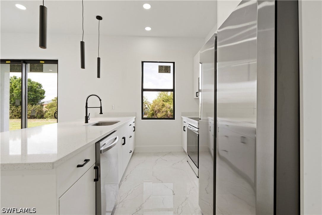 532 Lone Star Lane, Lehigh Acres, FL 33974 White cabinetry with dark hardware and a white countertop, stainless steel appliances, black pendant lighting, and large format tile flooring