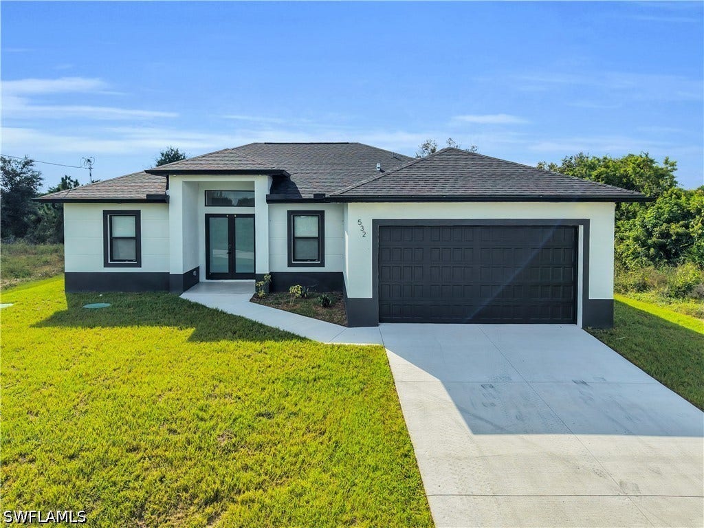 532 Lone Star Lane, Lehigh Acres, FL 33974 Contemporary exterior with a white and dark gray color scheme, a dark asphalt shingle roof, double front entry doors, and an attached two-car garage