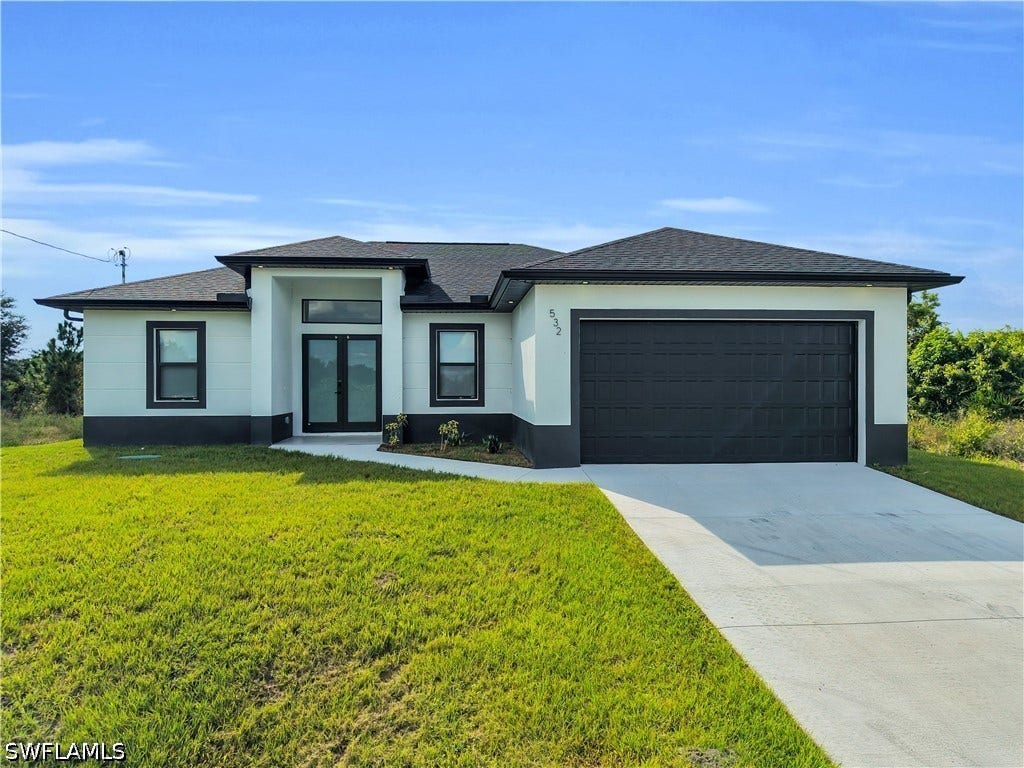 532 Lone Star Lane, Lehigh Acres, FL 33974 Contemporary exterior with a two-car garage, double entry doors, a transom window, and a concrete driveway