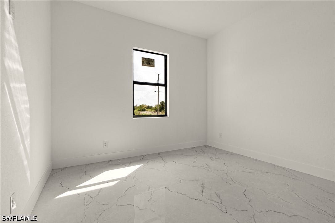 532 Lone Star Lane, Lehigh Acres, FL 33974 White walls complementing a window with dark framing and a tile floor with a veined pattern