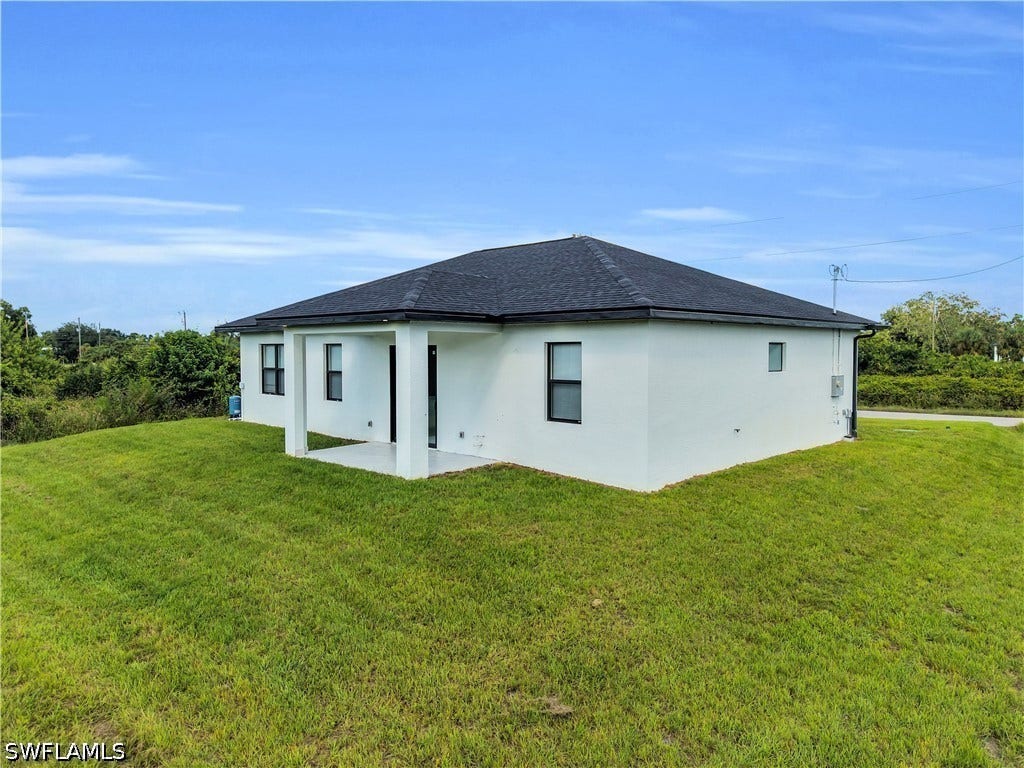 532 Lone Star Lane, Lehigh Acres, FL 33974 Contemporary single-story residence featuring a dark shingled roof, white stucco exterior, and black-framed windows