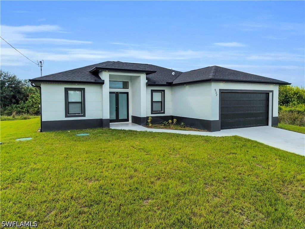 532 Lone Star Lane, Lehigh Acres, FL 33974 Contemporary architecture featuring a two-car garage, black framed windows, and a glass-paneled entry door