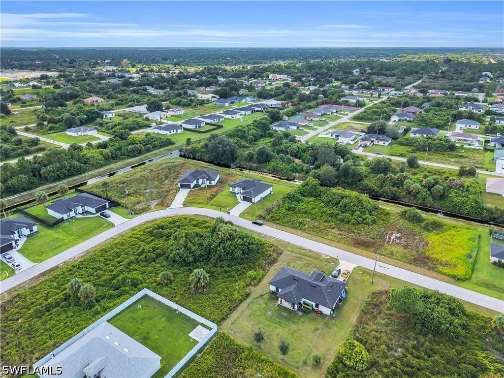 532 Lone Star Lane, Lehigh Acres, FL 33974 Aerial perspective of a residential neighborhood featuring single-story homes with dark roofs, paved streets, and green landscaping