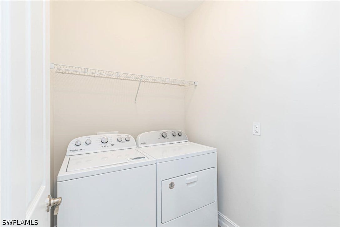 Washroom featuring independent washer and dryer and baseboards