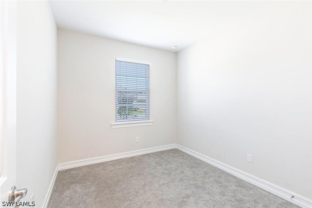 Carpeted spare room featuring baseboards