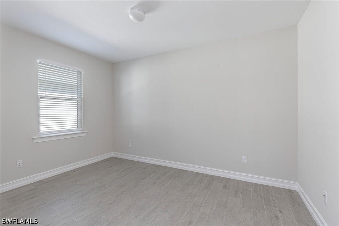 Unfurnished room with light wood-type flooring and baseboards