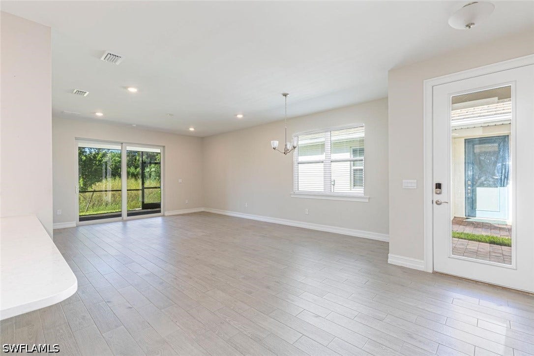 Unfurnished living room featuring plenty of natural light, recessed lighting, light wood-style flooring, and a chandelier