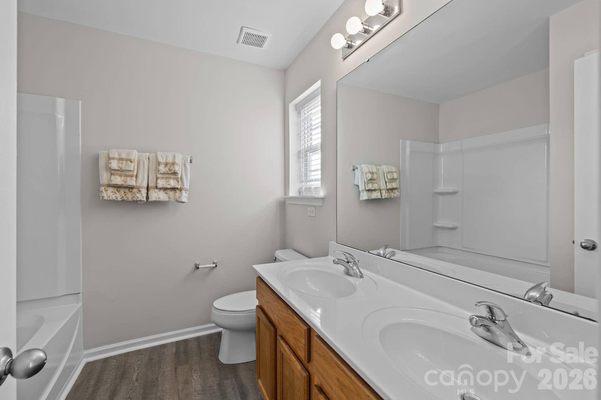 En-suite bathroom features double sink vanity with mirrored medicine cabinet and window providing excellent natural light.