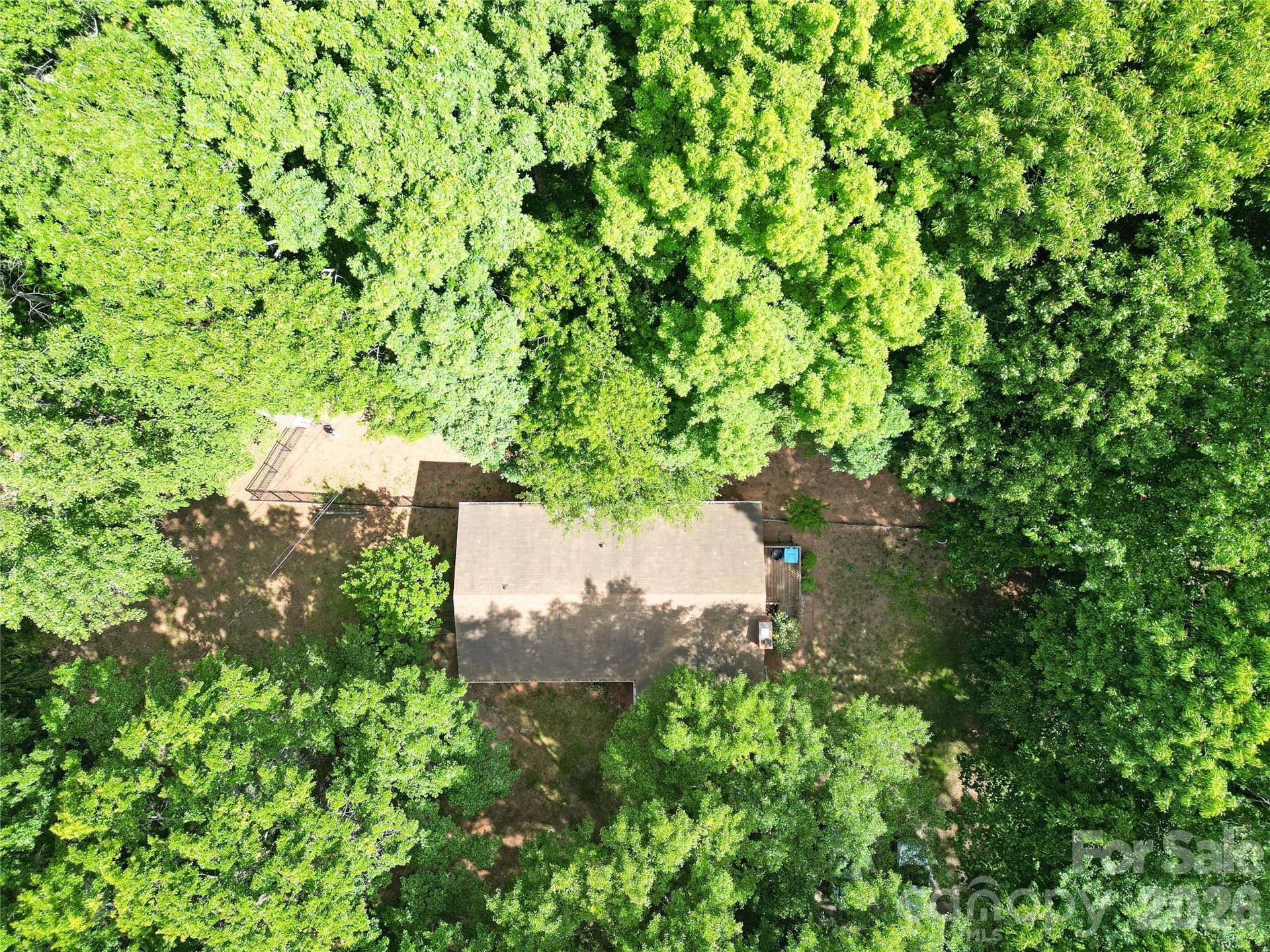 Aerial view of home with surrounding woods.