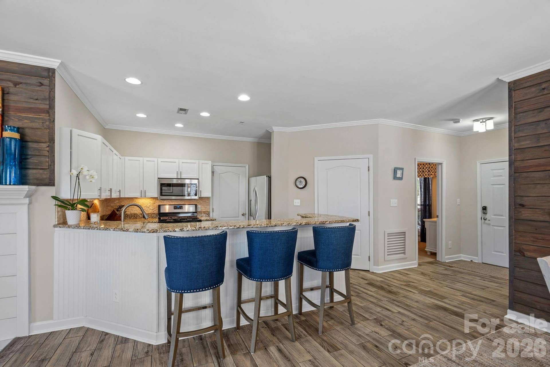 Open kitchen with counter seating for casual meals or entertaining. Laundry room off kitchen features built-in shelving for pantry items.