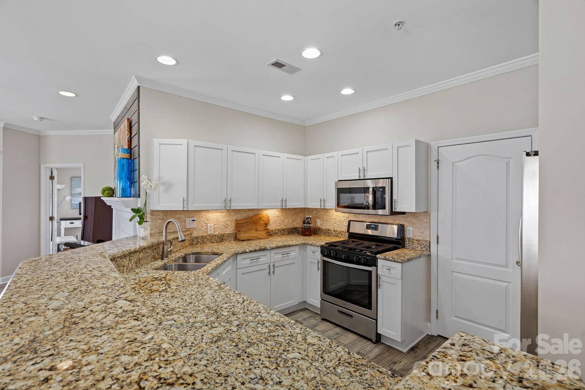Open kitchen with counter seating for casual meals or entertaining. Laundry room off kitchen features built-in shelving for pantry items.
