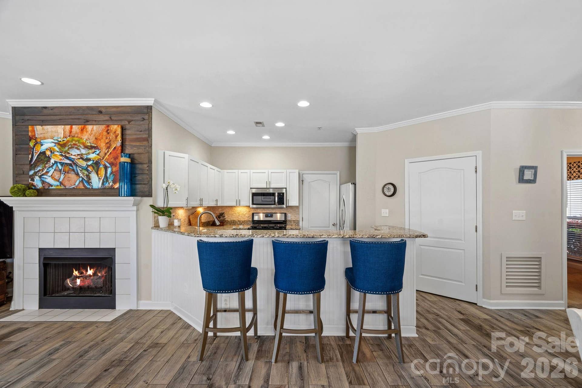 Open kitchen with counter seating for casual meals or entertaining. Laundry room off kitchen features built-in shelving for pantry items.