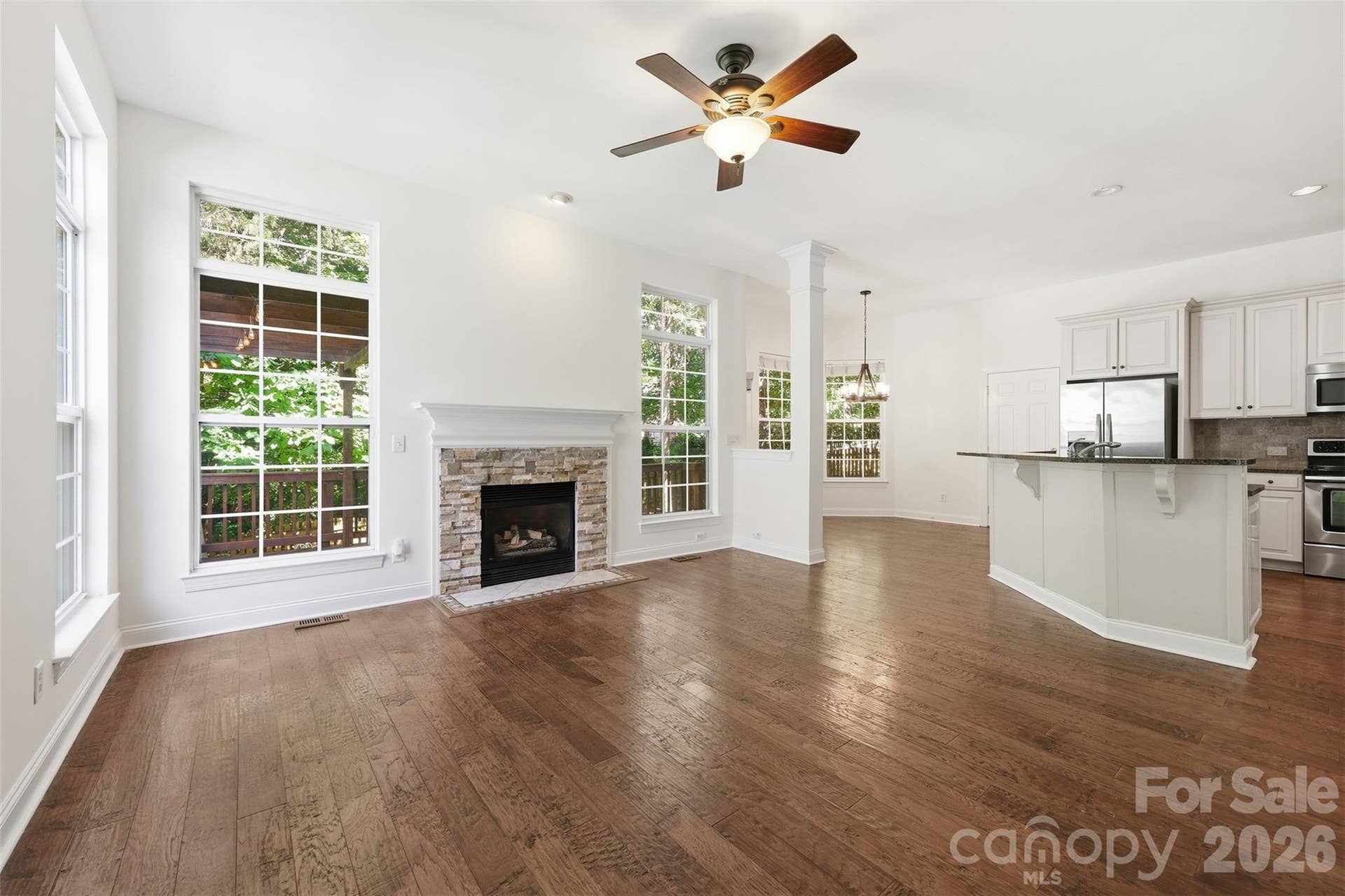 6832 Charter Hills Road, Charlotte, NC 28277 Living Room features a stunning gas fireplace with a stacked stone surround & hand-scraped wide plank hardwood floors