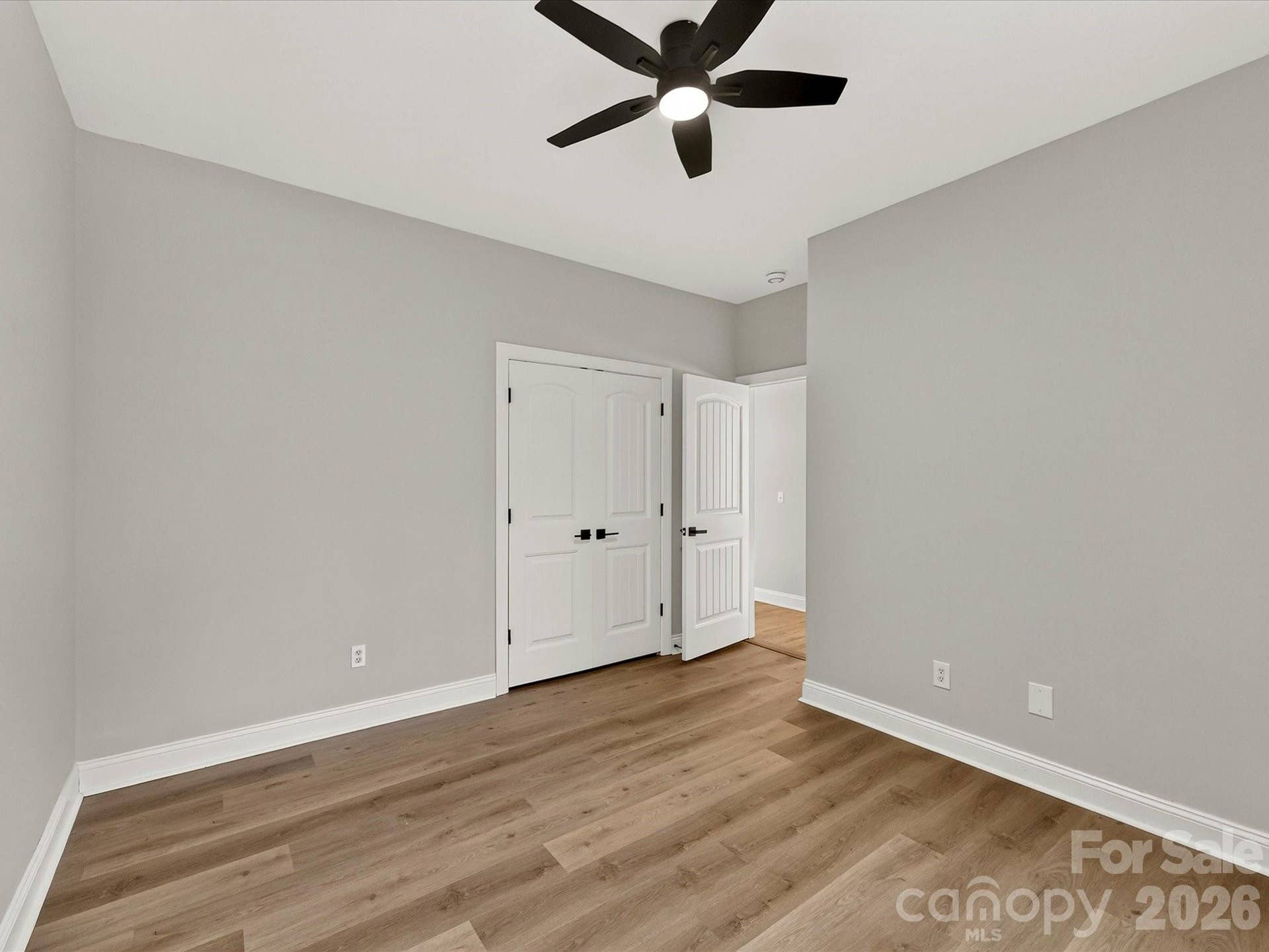 Bedroom 2 offers a bright and comfortable retreat with luxury vinyl plank flooring, a ceiling fan, generous closet space, and a large window overlooking the backyard.