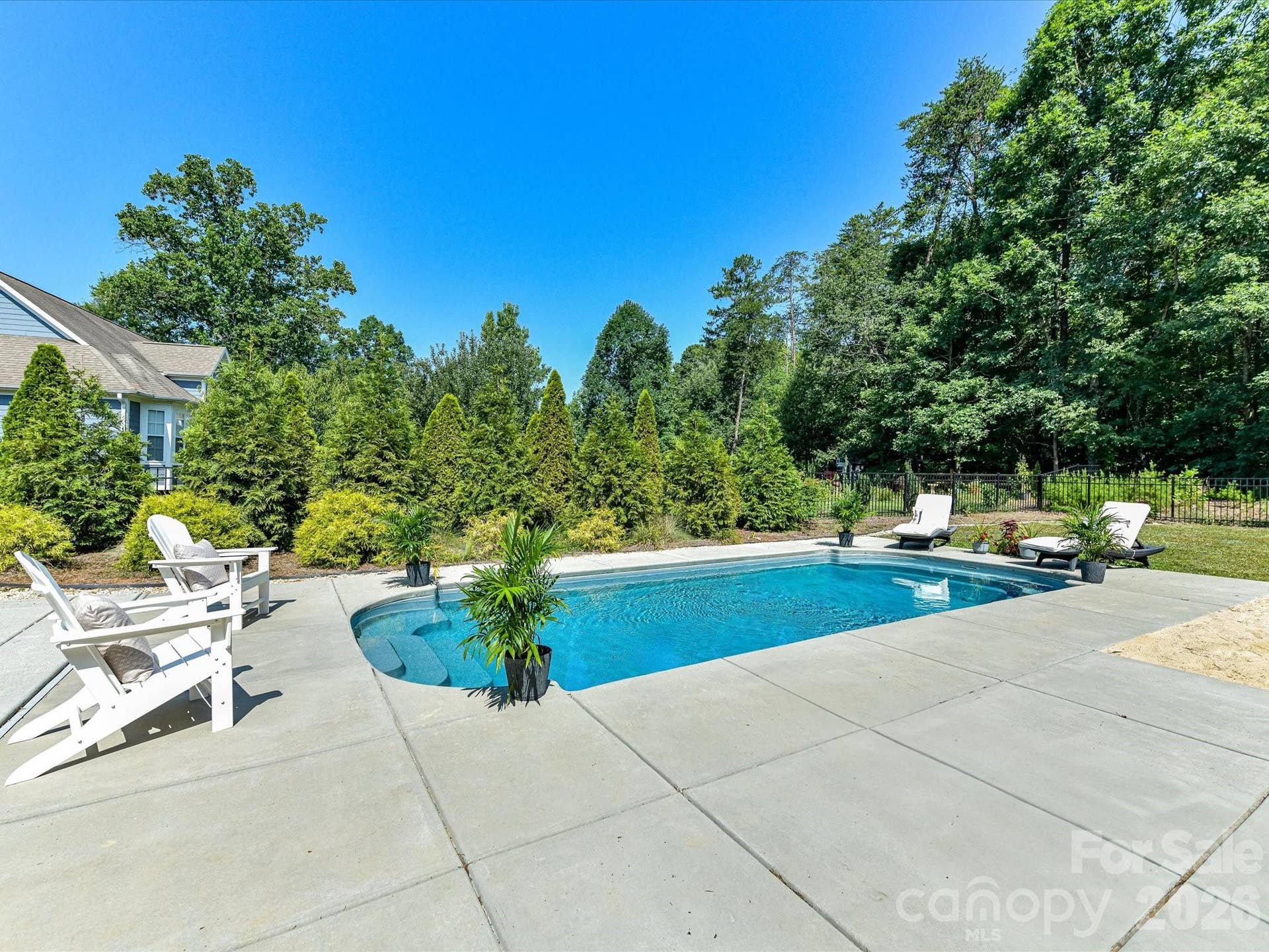 The sparkling in ground pool creates a private backyard retreat, surrounded by spacious patio areas and mature landscaping for relaxing and entertaining.