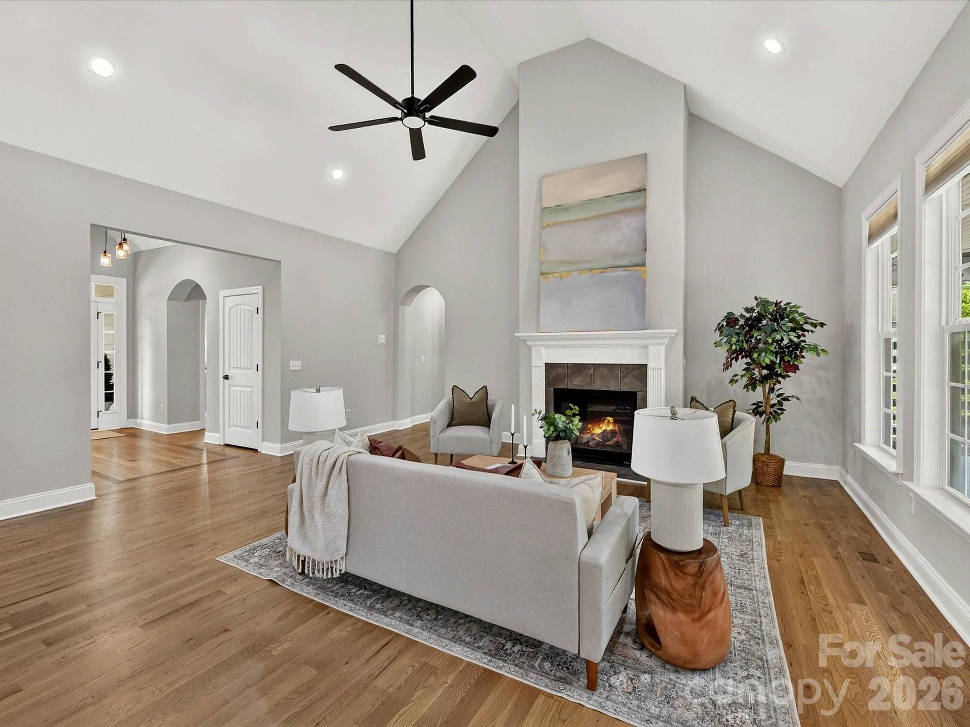 The impressive Great Room showcases soaring vaulted ceilings, rich wood floors, a cozy fireplace, and expansive windows that fill the space with natural light.