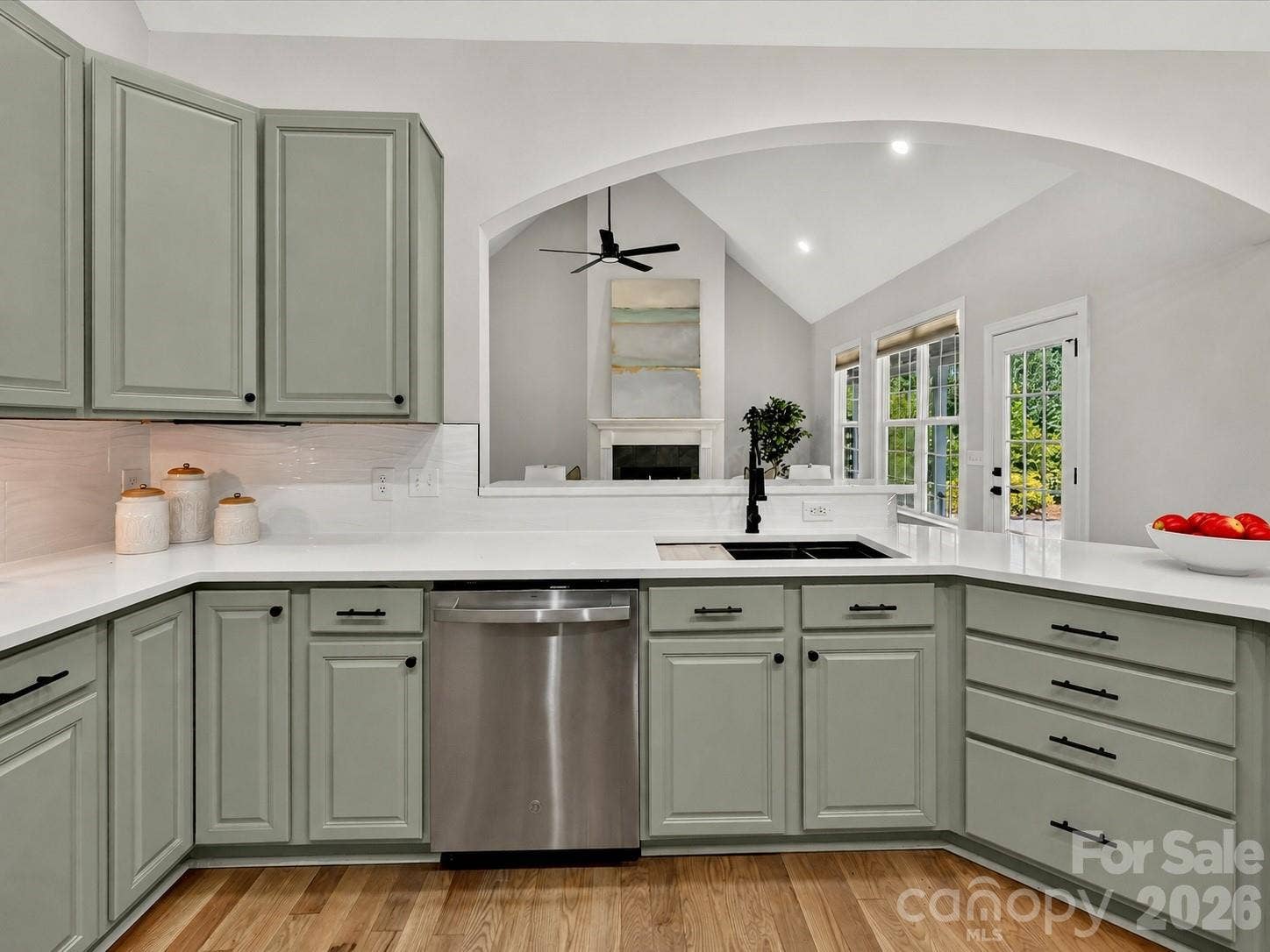 This beautifully appointed kitchen features quartz countertops, stainless steel appliances, abundant painted cabinetry, a spacious breakfast bar, and an open layout designed for both everyday living and effortless entertaining.