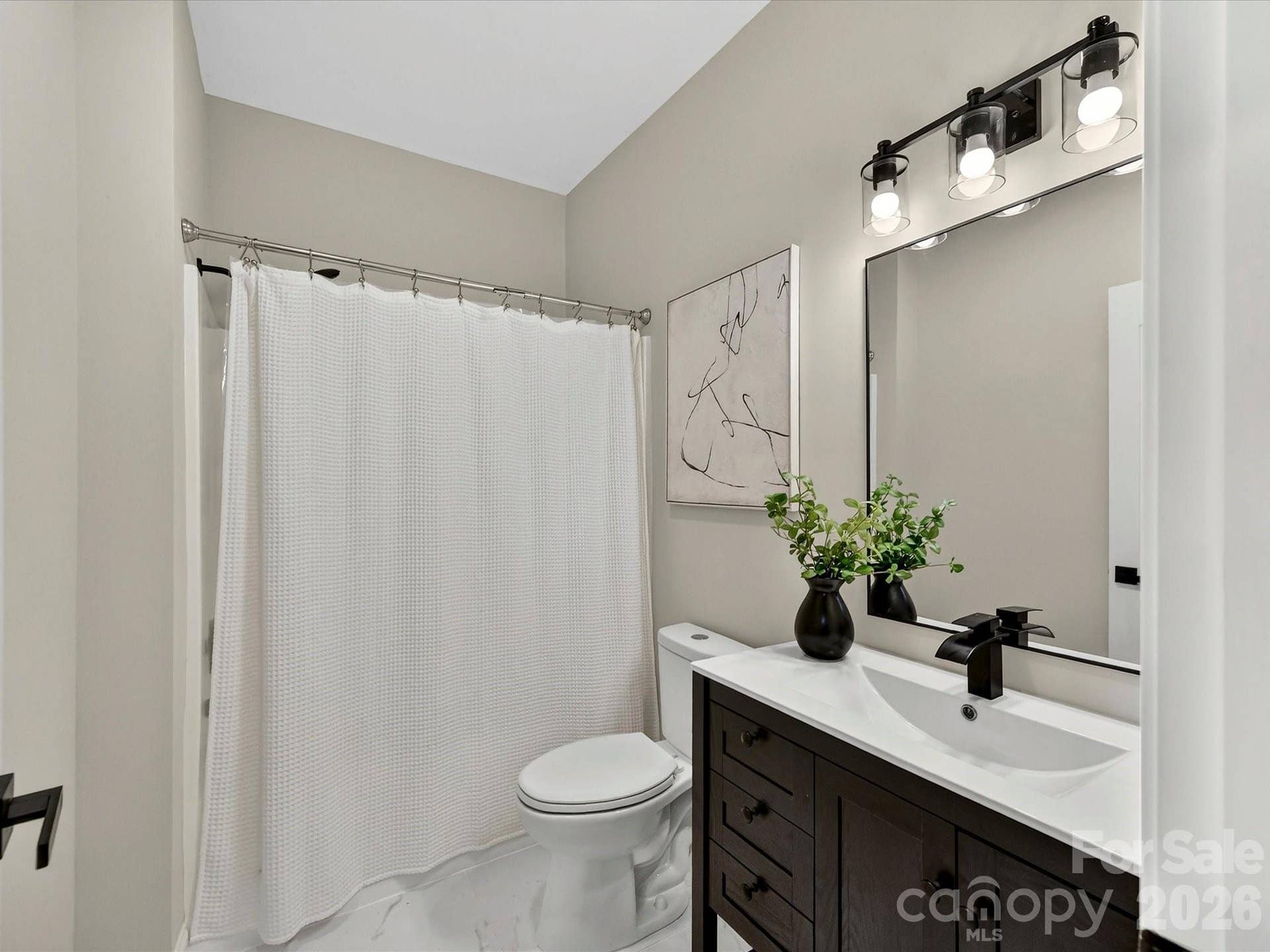 The well appointed full bath features a modern vanity, stylish black fixtures, and a tub and shower combination with a clean contemporary design.