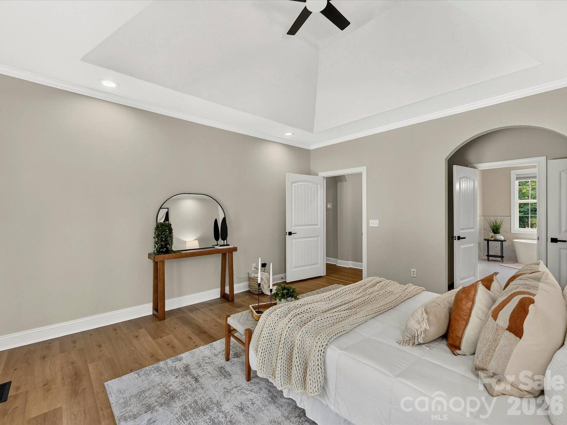 The spacious main level primary suite offers a relaxing retreat with a tray ceiling, abundant natural light, LVP floors, and direct access to the luxurious ensuite bath.