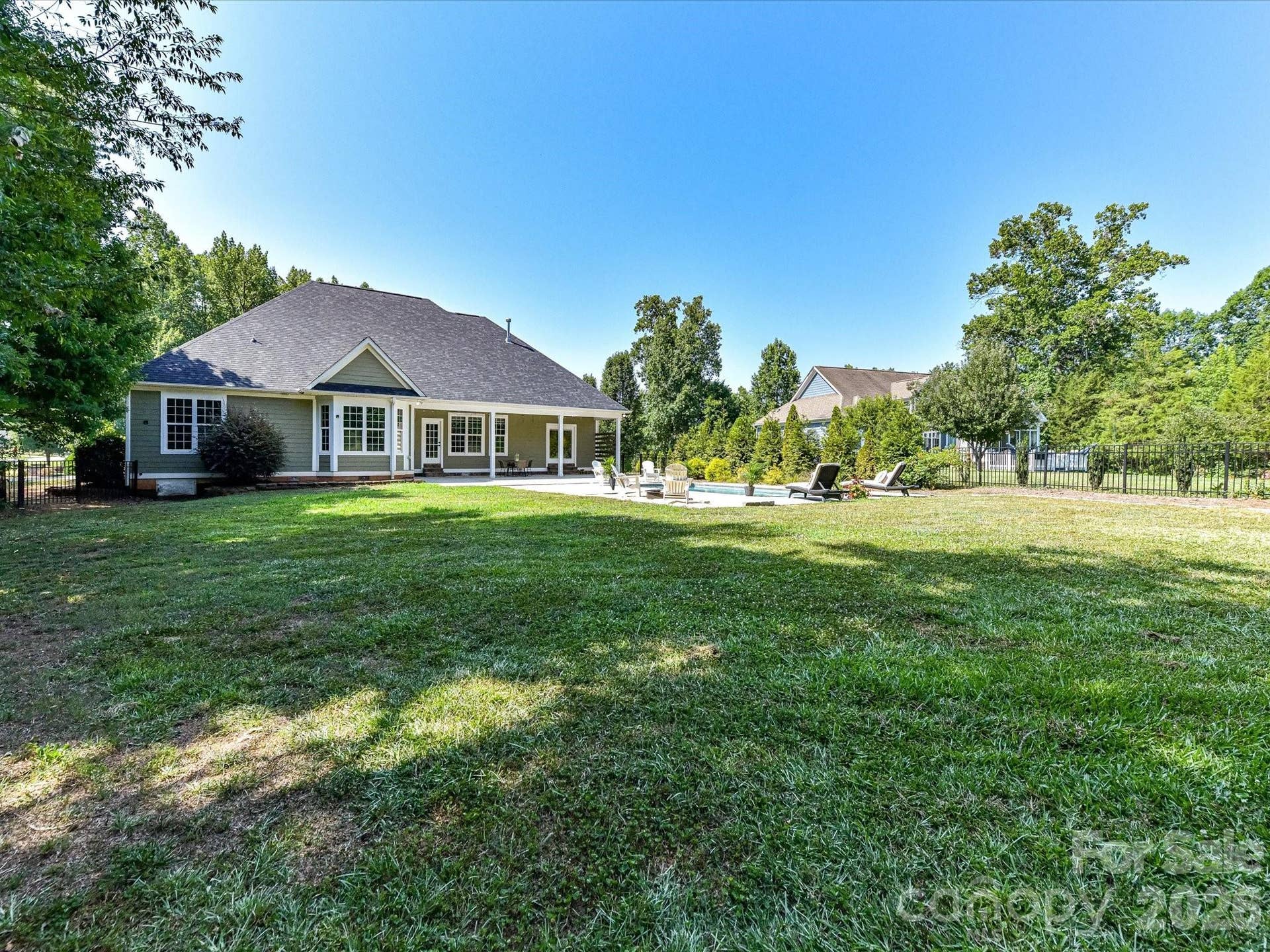 The expansive backyard offers a large, level lawn, sparkling pool, and covered patio, creating the perfect setting for outdoor entertaining, recreation, and relaxation.