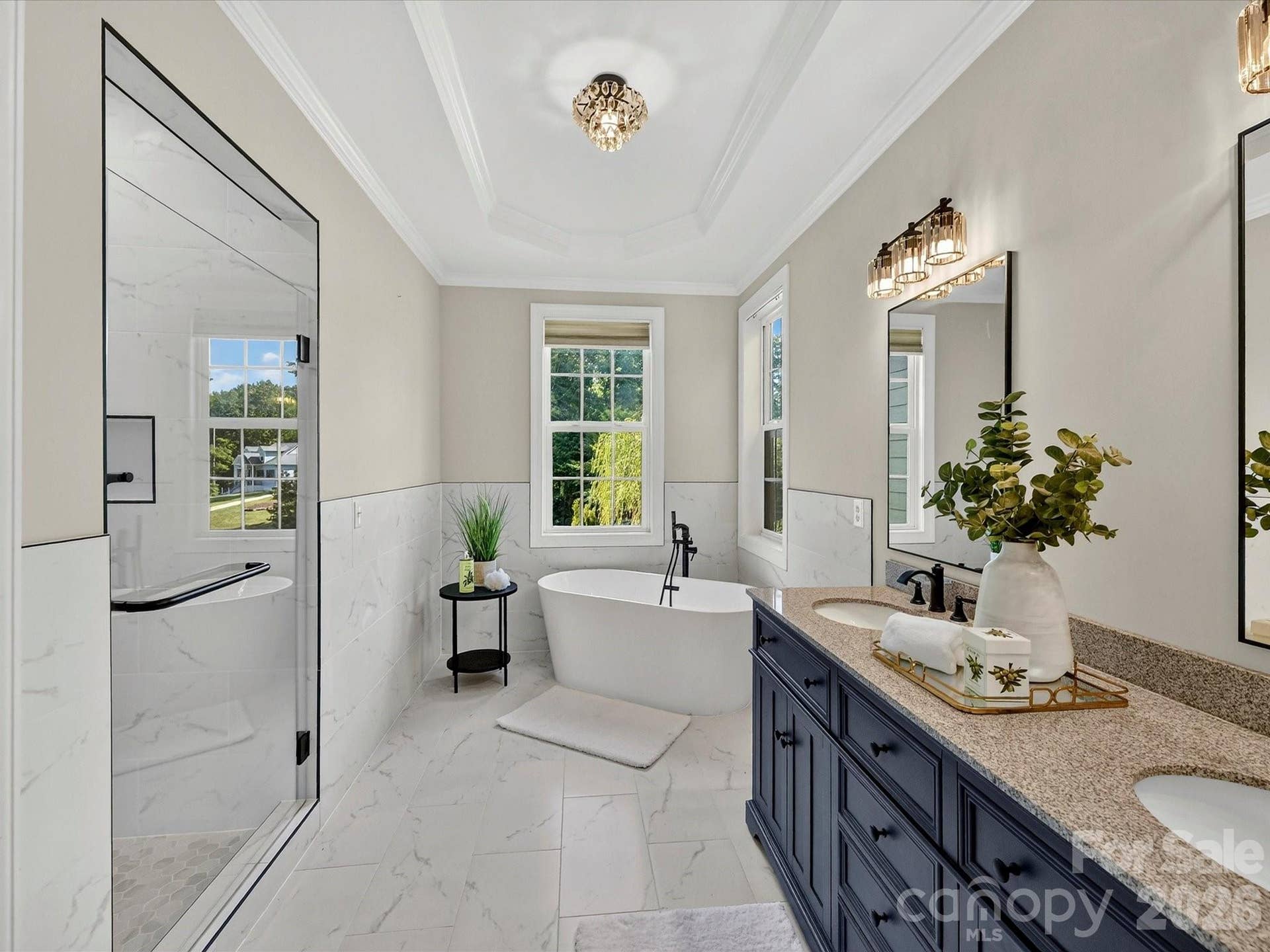 The luxurious primary bath offers a spa inspired retreat with dual granite vanities, a freestanding soaking tub, an oversized tiled walk in shower, and elegant designer finishes throughout.