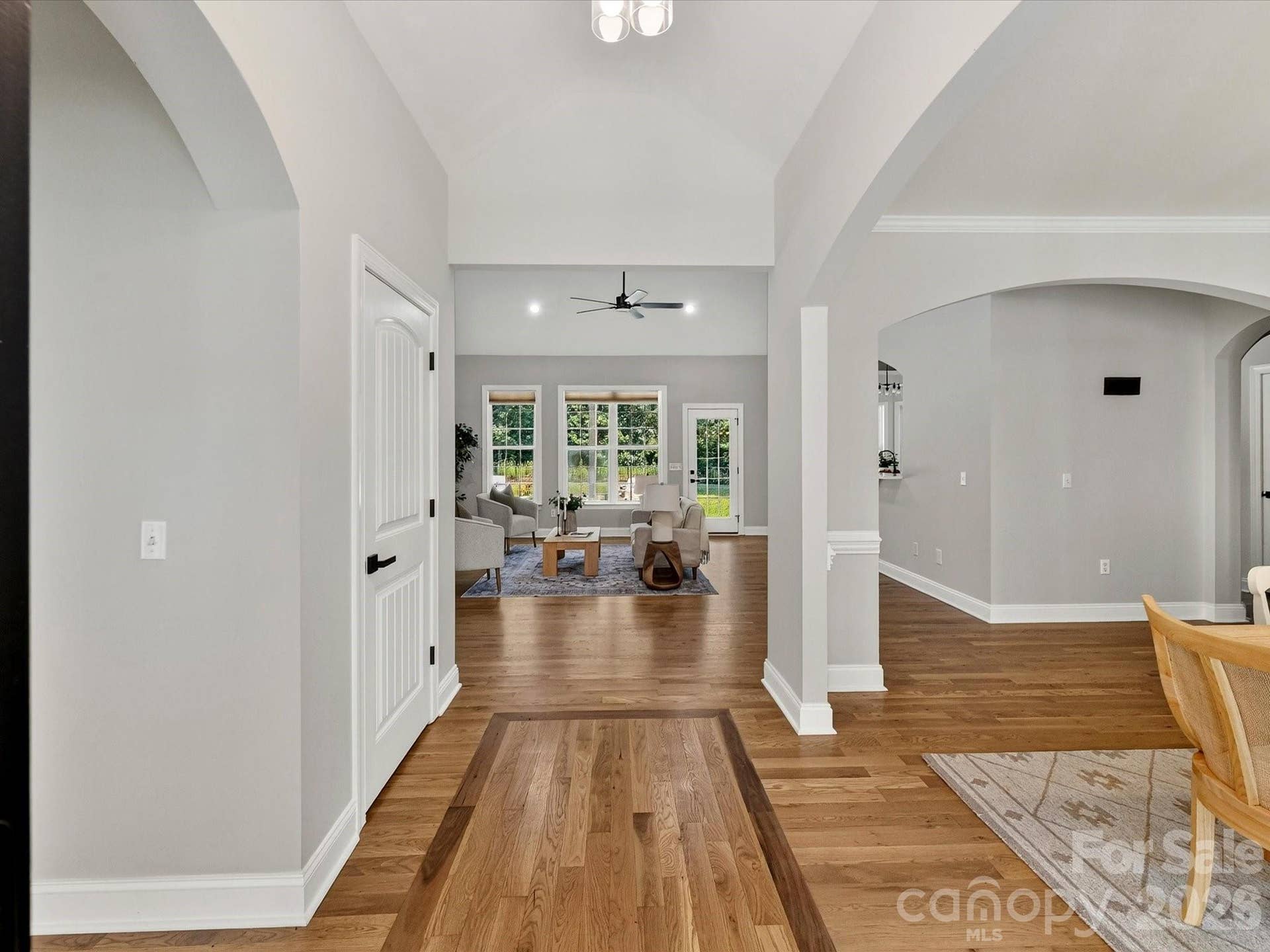 A dramatic vaulted foyer with wood floors and elegant arched openings creates a bright and welcoming introduction to the home's open-concept design.