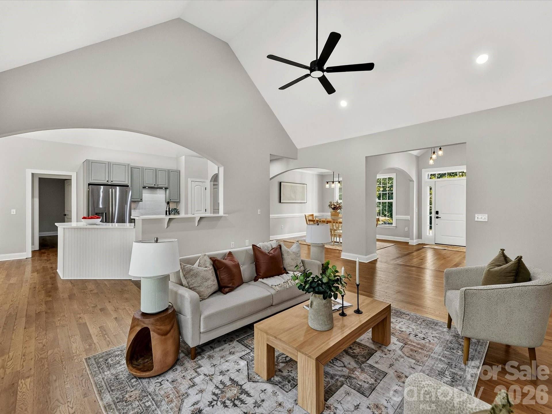 The impressive Great Room showcases soaring vaulted ceilings, rich wood floors, a cozy fireplace, and expansive windows that fill the space with natural light.