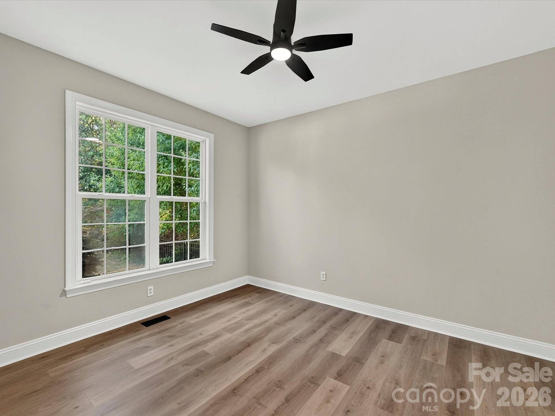 Bedroom 2 offers a bright and comfortable retreat with luxury vinyl plank flooring, a ceiling fan, generous closet space, and a large window overlooking the backyard.