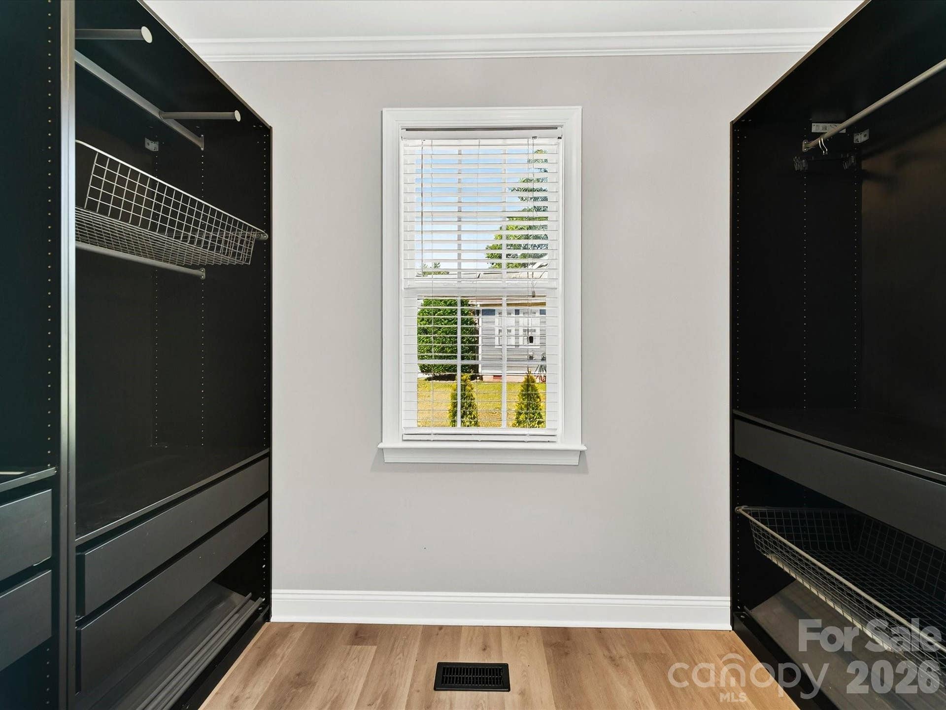 The spacious walk in primary closet features custom built in organization systems, abundant storage, and a window that fills the space with natural light.
