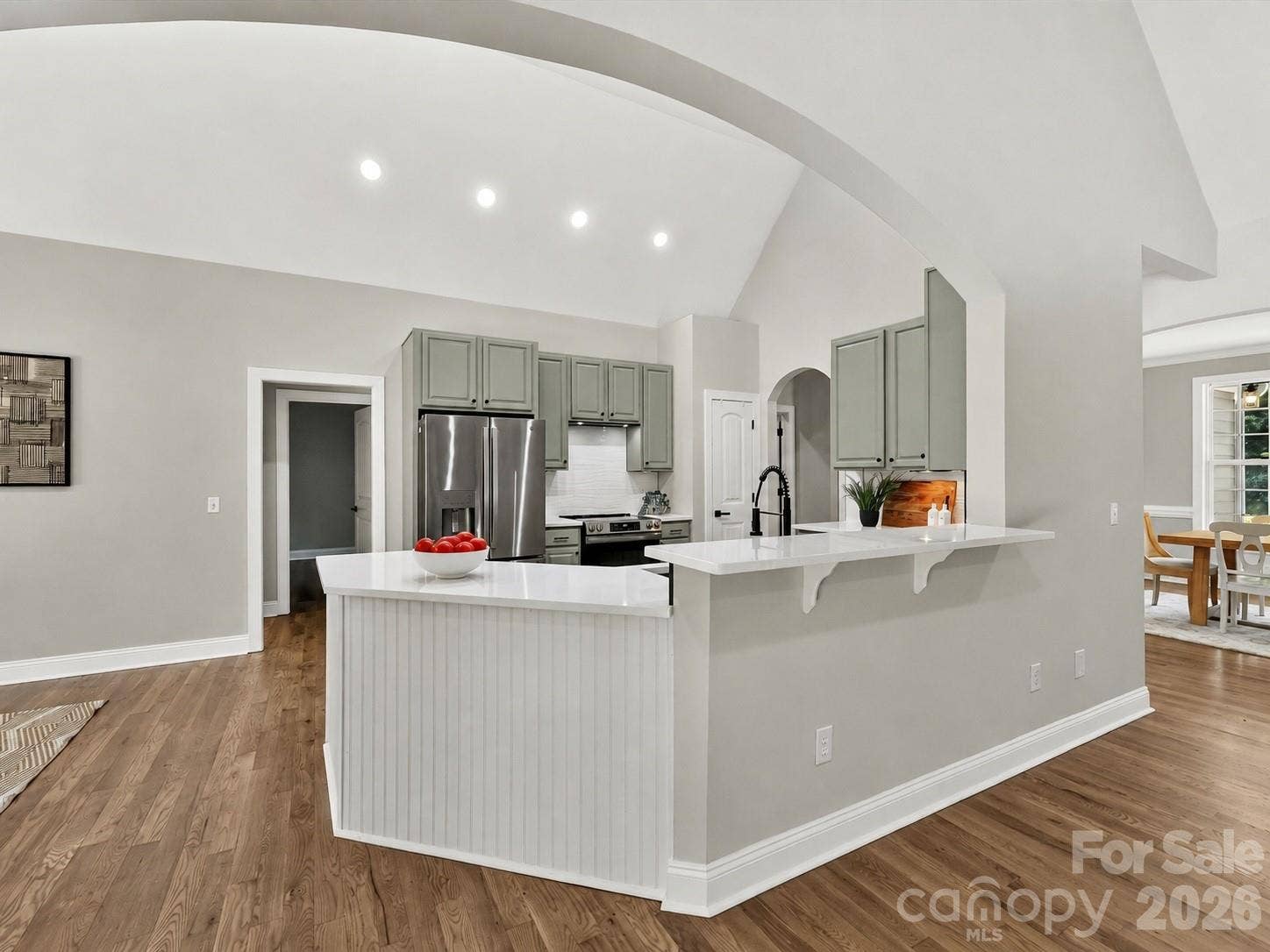 The beautifully designed kitchen features vaulted ceilings, quartz countertops, abundant cabinetry, a breakfast bar, and an open layout that flows seamlessly into the surrounding living spaces.