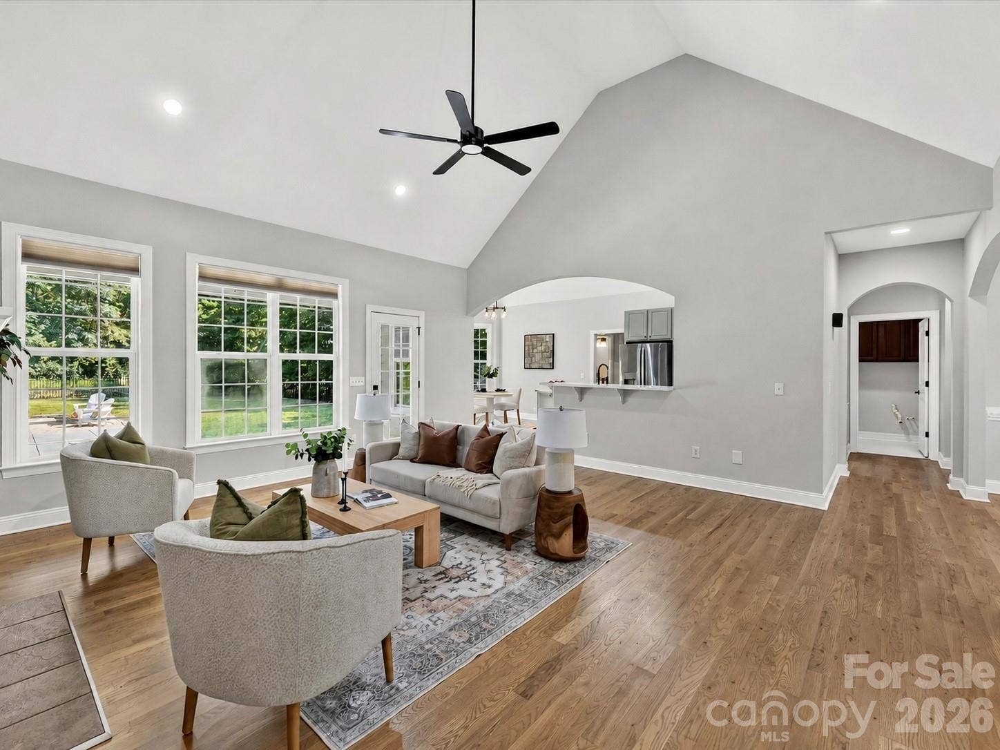 The impressive Great Room showcases soaring vaulted ceilings, rich wood floors, a cozy fireplace, and expansive windows that fill the space with natural light.