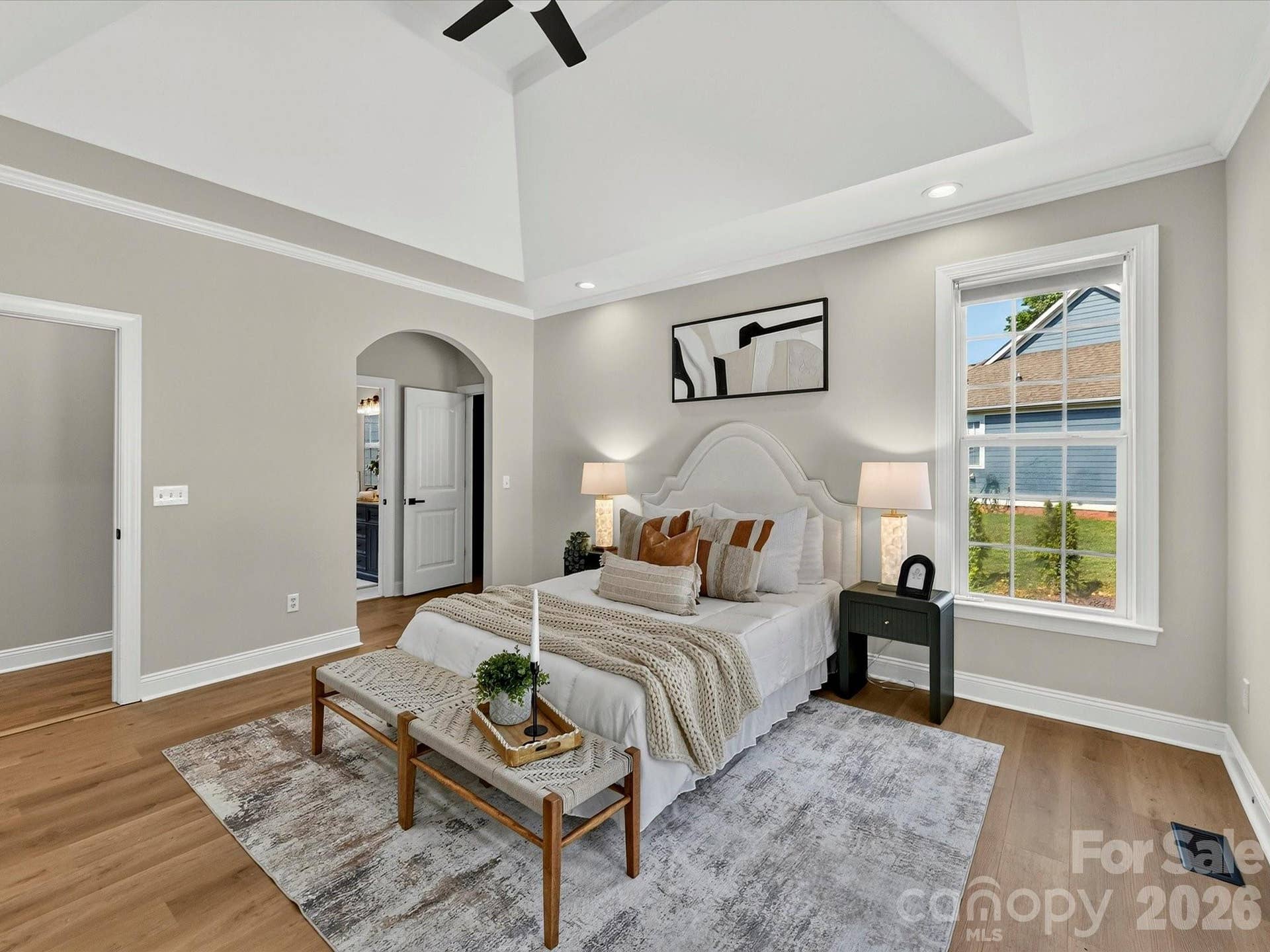 The spacious main level primary suite offers a relaxing retreat with a tray ceiling, abundant natural light, LVP floors, and direct access to the luxurious ensuite bath.