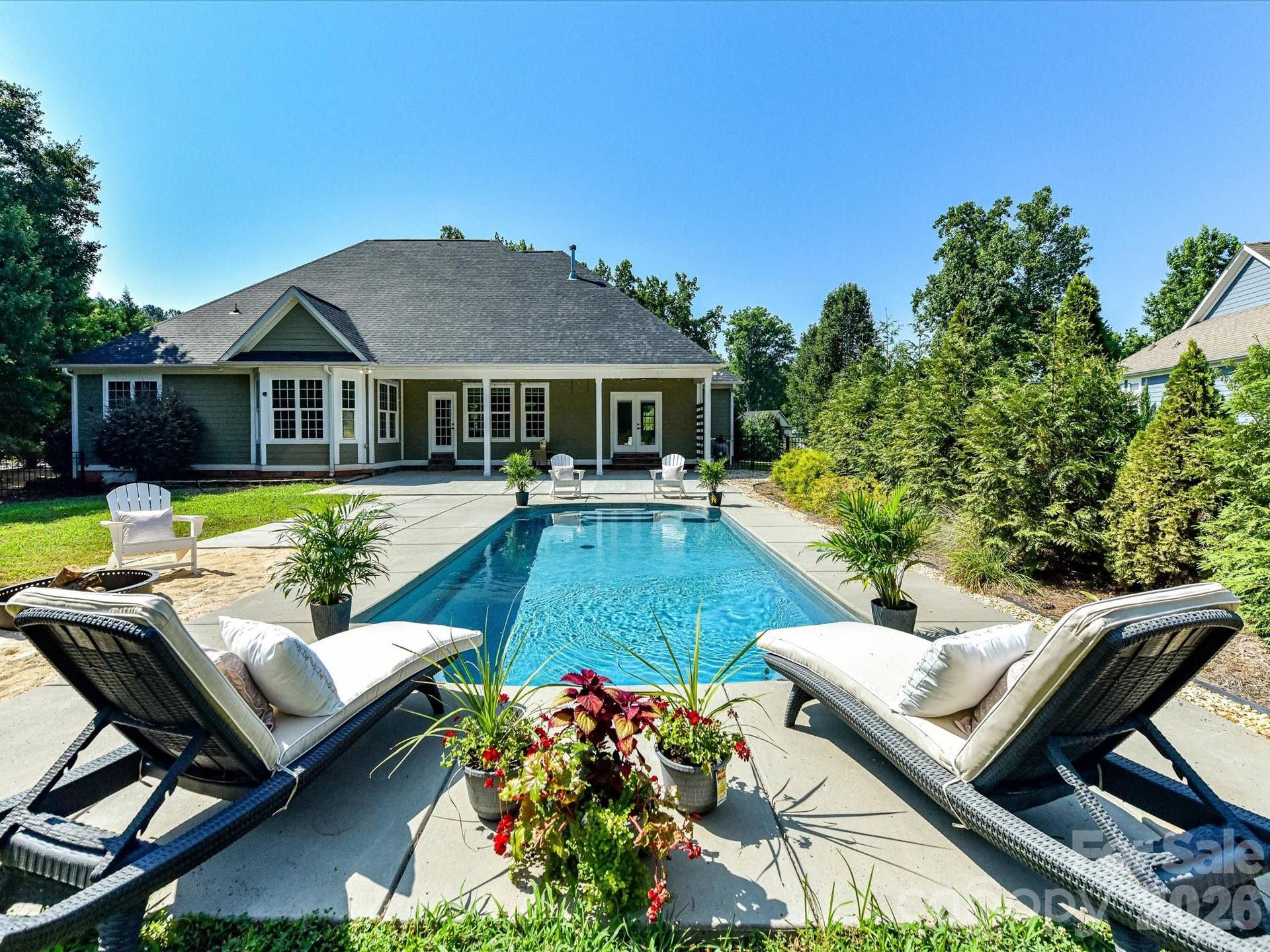 Resort-style outdoor living awaits with a sparkling in-ground pool, expansive patio, covered porch, and a private backyard designed for relaxing and entertaining.