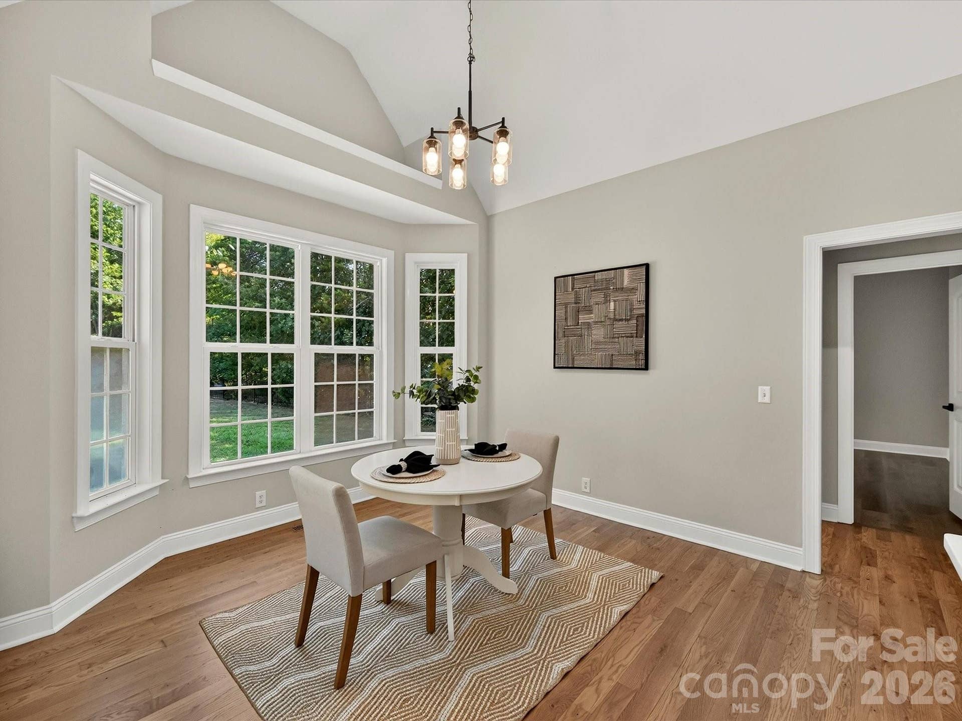 The bright breakfast nook features vaulted ceilings, a wall of windows overlooking the backyard and pool, and an inviting space for casual dining filled with natural light.