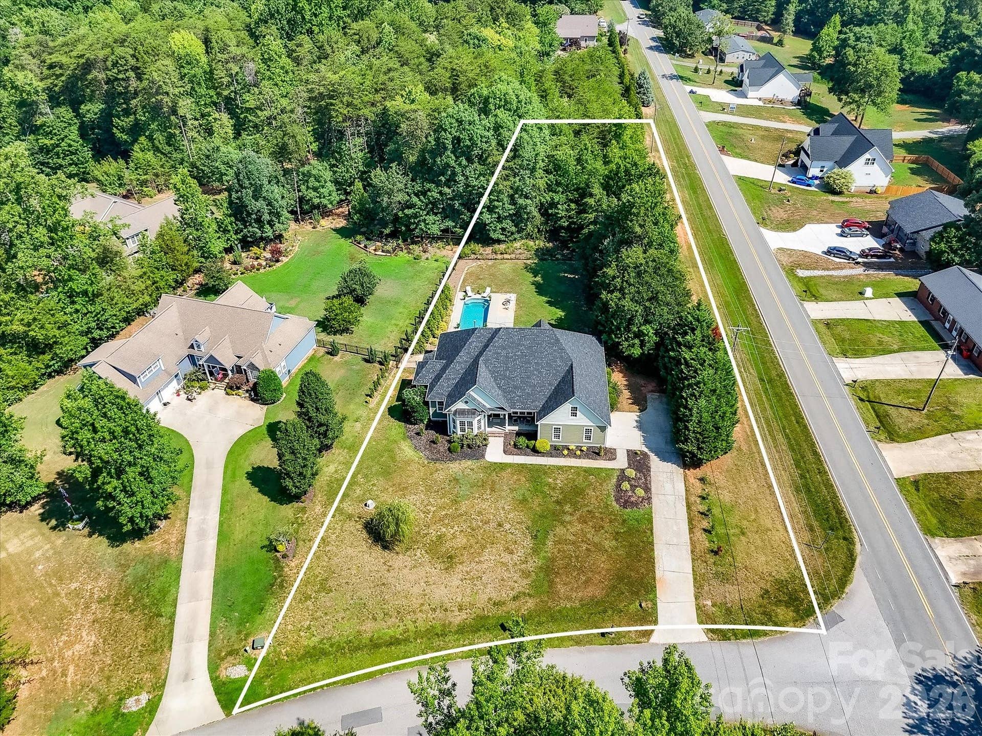 The aerial view with property lines (boundary lines are approximate) clearly showcases the expansive homesite, private setting, and generous backyard with pool surrounded by mature trees.