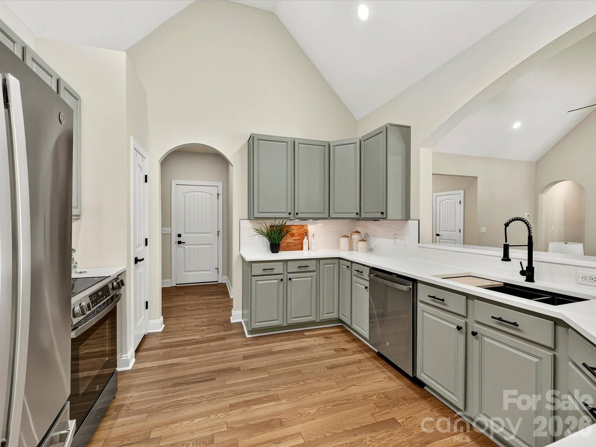 This beautifully appointed kitchen features quartz countertops, stainless steel appliances, abundant painted cabinetry, a spacious breakfast bar, and an open layout designed for both everyday living and effortless entertaining.