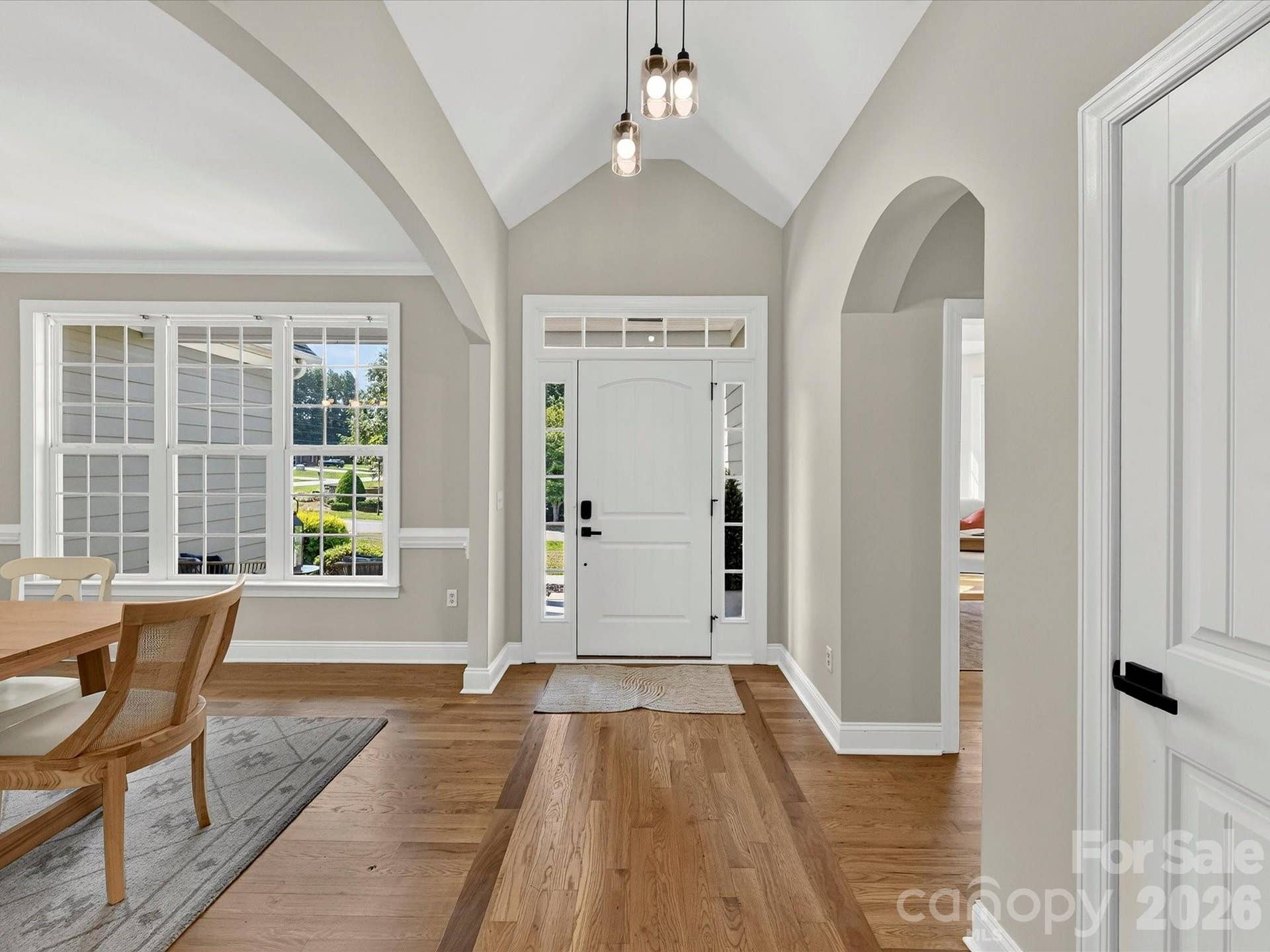 A dramatic vaulted foyer with wood floors and elegant arched openings creates a bright and welcoming introduction to the home's open-concept design.