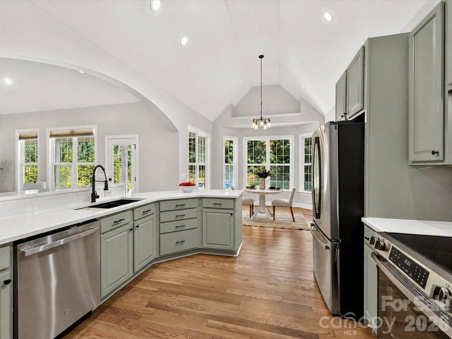 This beautifully appointed kitchen features quartz countertops, stainless steel appliances, abundant painted cabinetry, a spacious breakfast bar, and an open layout designed for both everyday living and effortless entertaining.