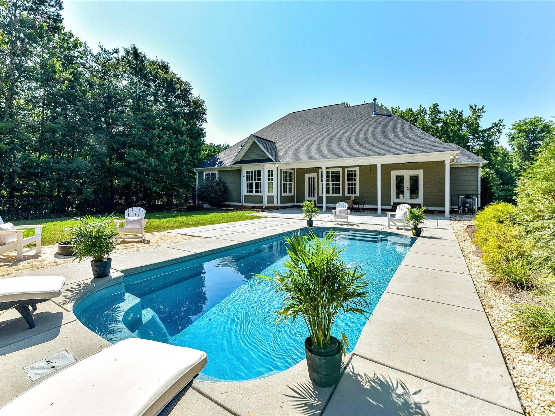 The sparkling in ground pool creates a private backyard retreat, surrounded by spacious patio areas and mature landscaping for relaxing and entertaining.