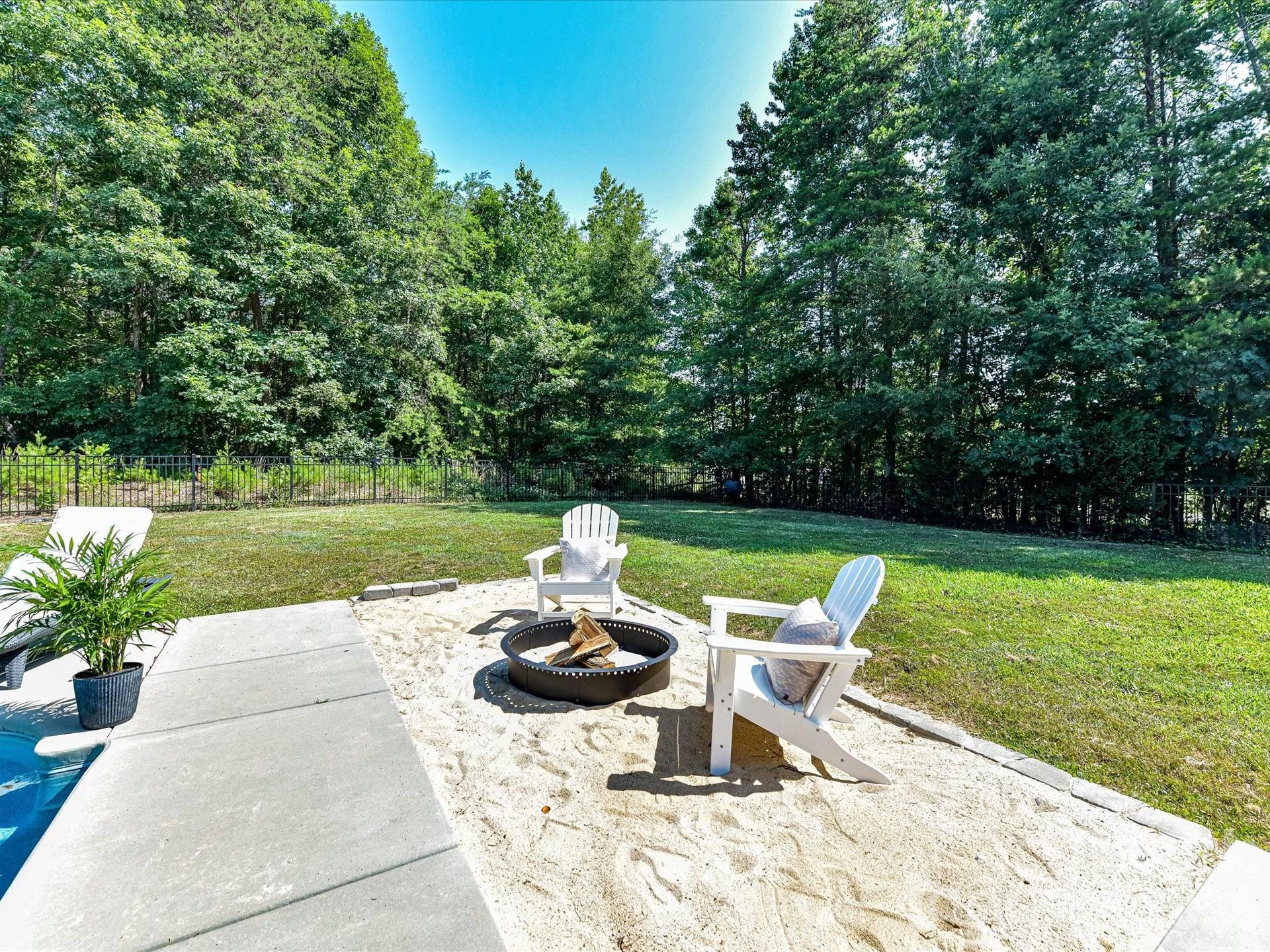 The poolside seating area with a fire pit creates the perfect space for gathering with family and friends while enjoying the private backyard setting.