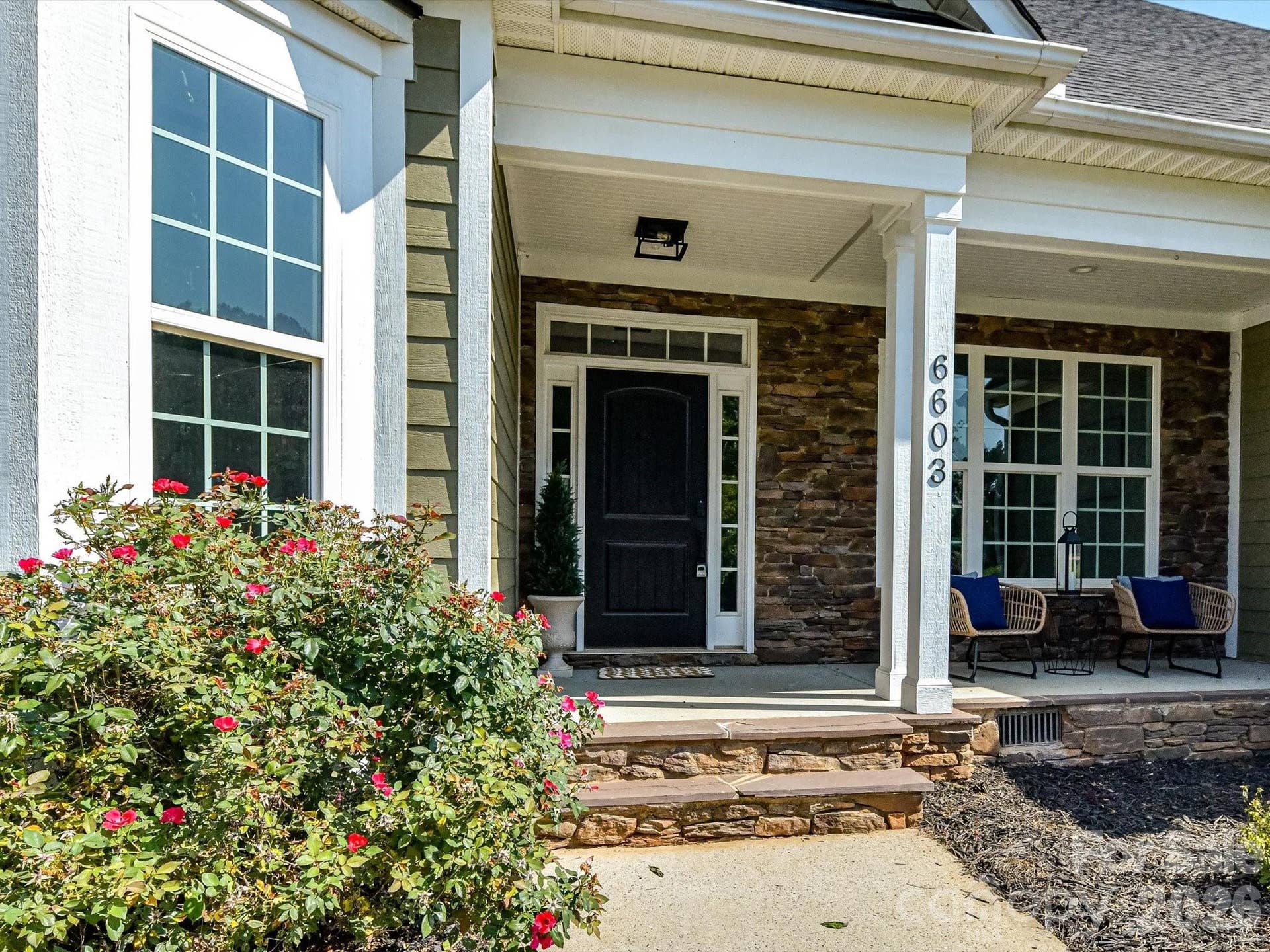 The inviting covered front porch with stacked stone accents offers the perfect place to relax and welcome guests in style.
