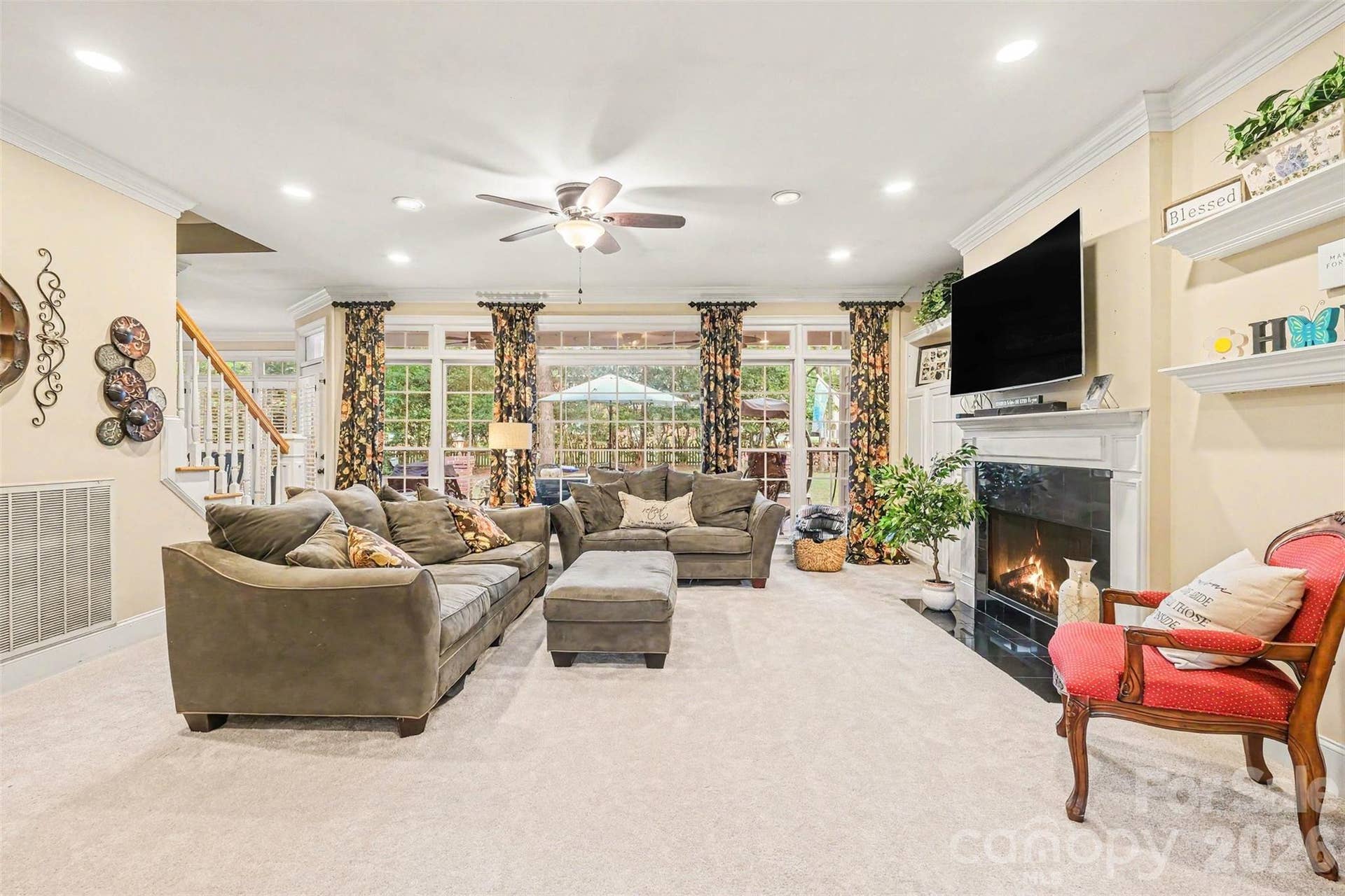 Living room with a wall of windows for great natural light-Virtually enhanced fireplace