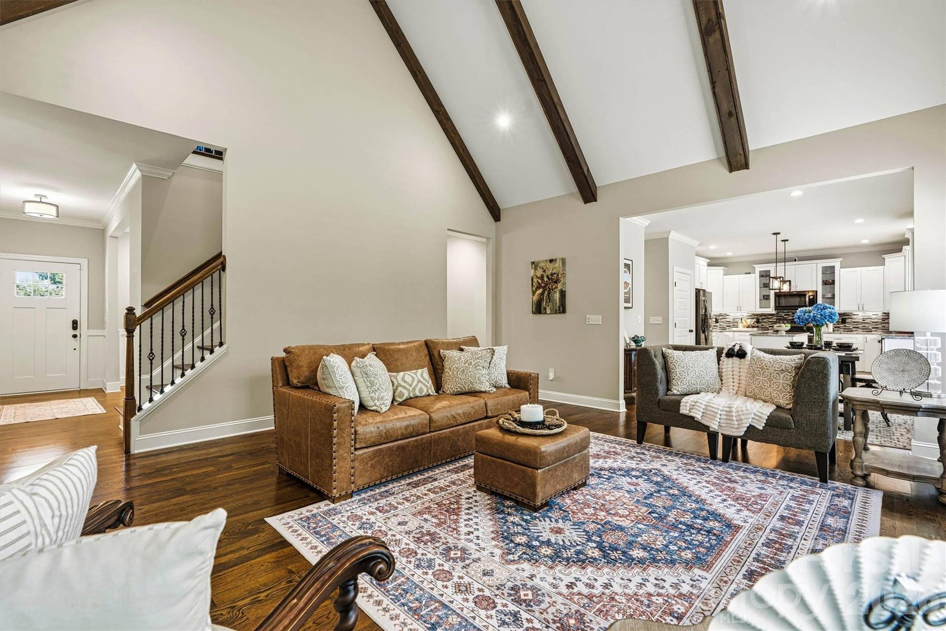 Great room has cathedral ceilings, exposed beams and stone fireplace with wood mantle