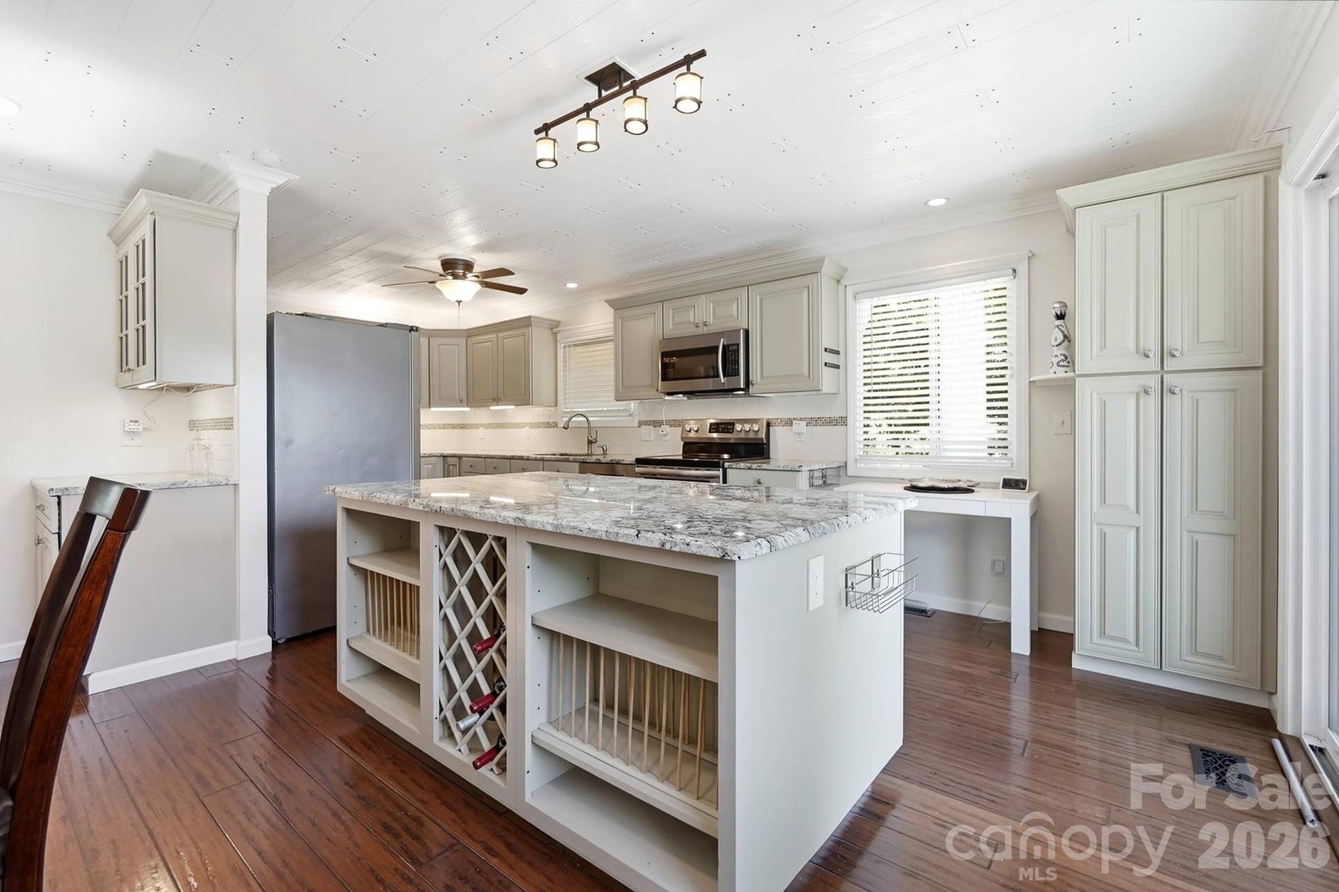 he gourmet kitchen features stainless steel appliances, granite countertops, a center island, and flows seamlessly into the dining room with a cozy fireplace
